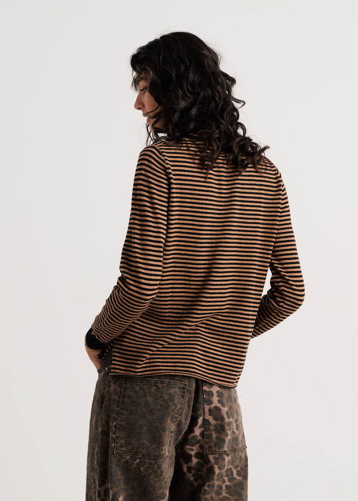 A model shown from the back wearing a brown and black horizontally striped long-sleeve shirt and leopard-print pants against a plain light gray background.