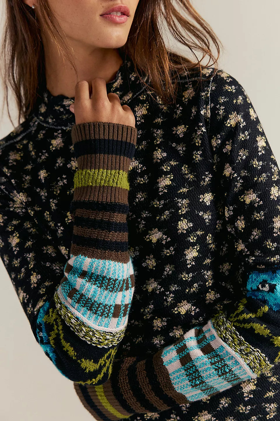 Close-up of a person wearing a patterned sweater with a colorful striped sleeve.