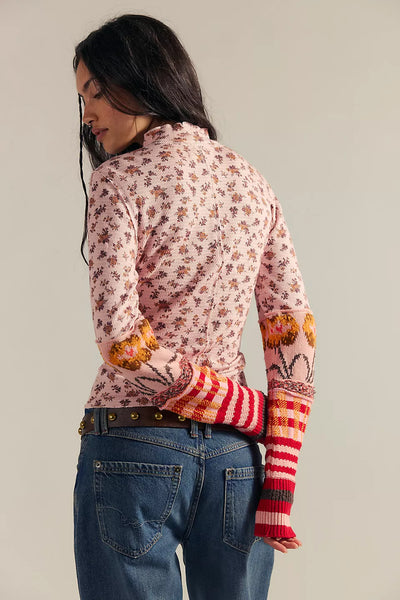 Person wearing a floral long-sleeve shirt with colorful sleeves and jeans on a plain background