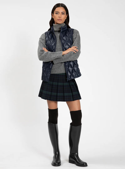 Woman wearing a gray sweater, plaid skirt, and black rain boots on a white background