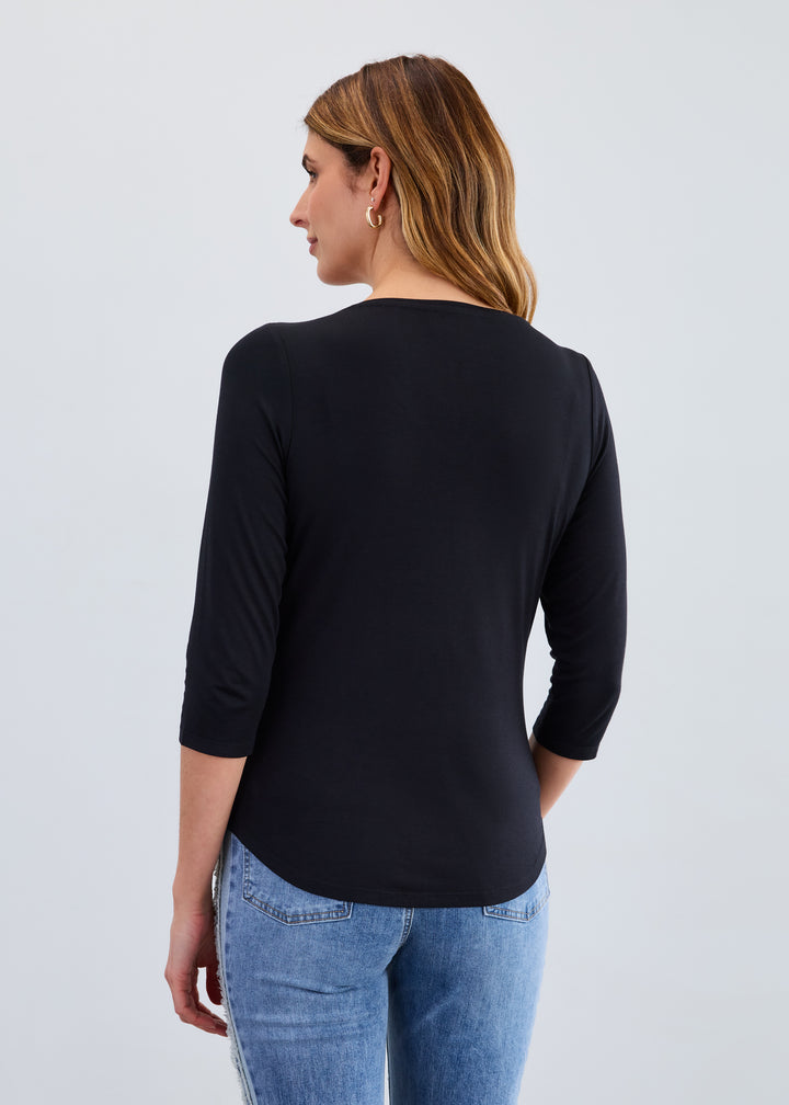 Woman wearing a black long-sleeve top and blue jeans on a light gray background