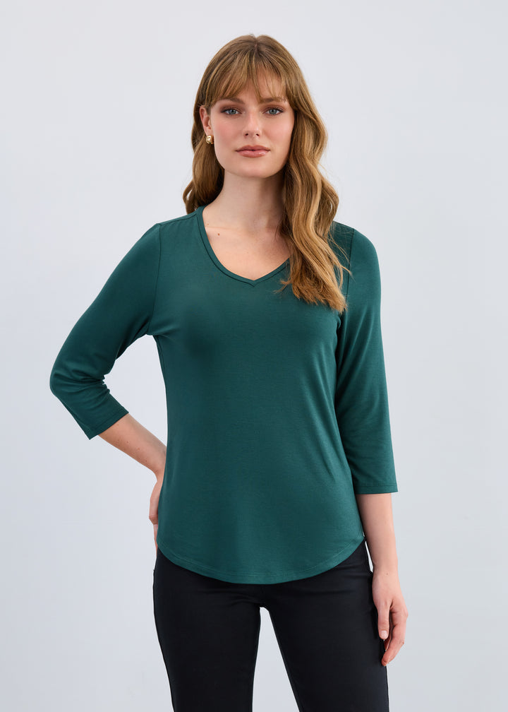 Woman wearing a green long-sleeve top against a white background