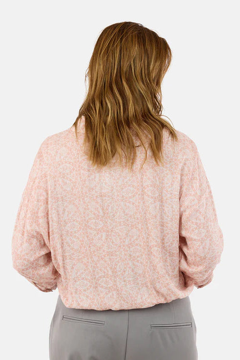 Person wearing a pink blouse and gray pants on a white background