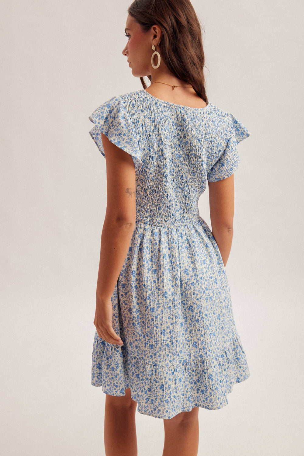 Woman wearing a blue floral dress on a plain background