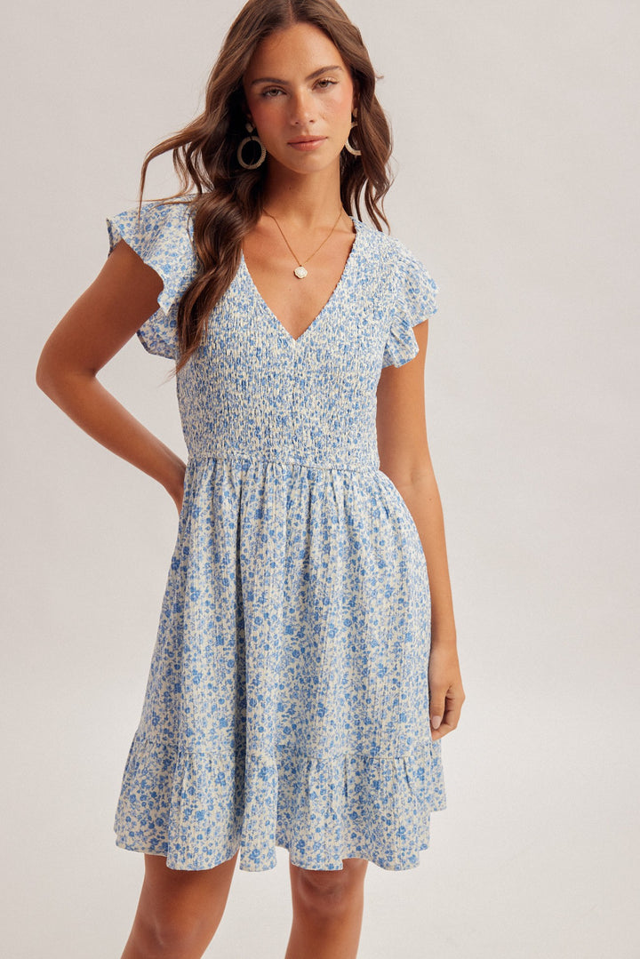 Woman wearing a blue floral dress on a plain background