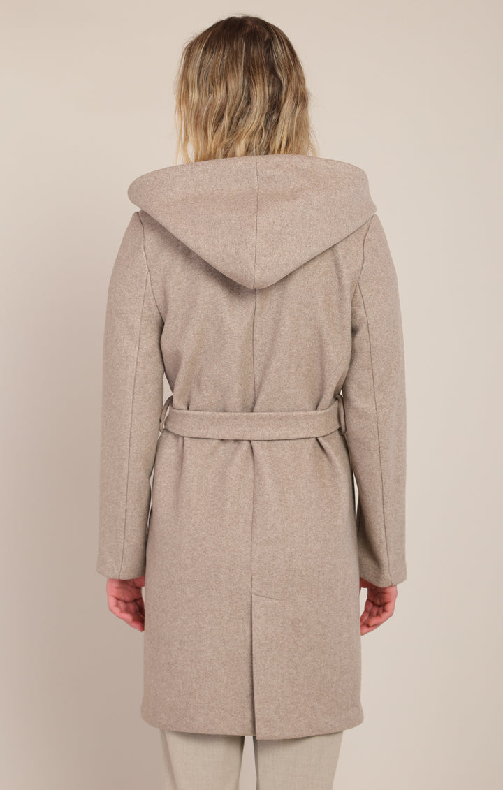 Woman wearing a beige hooded coat on a plain background