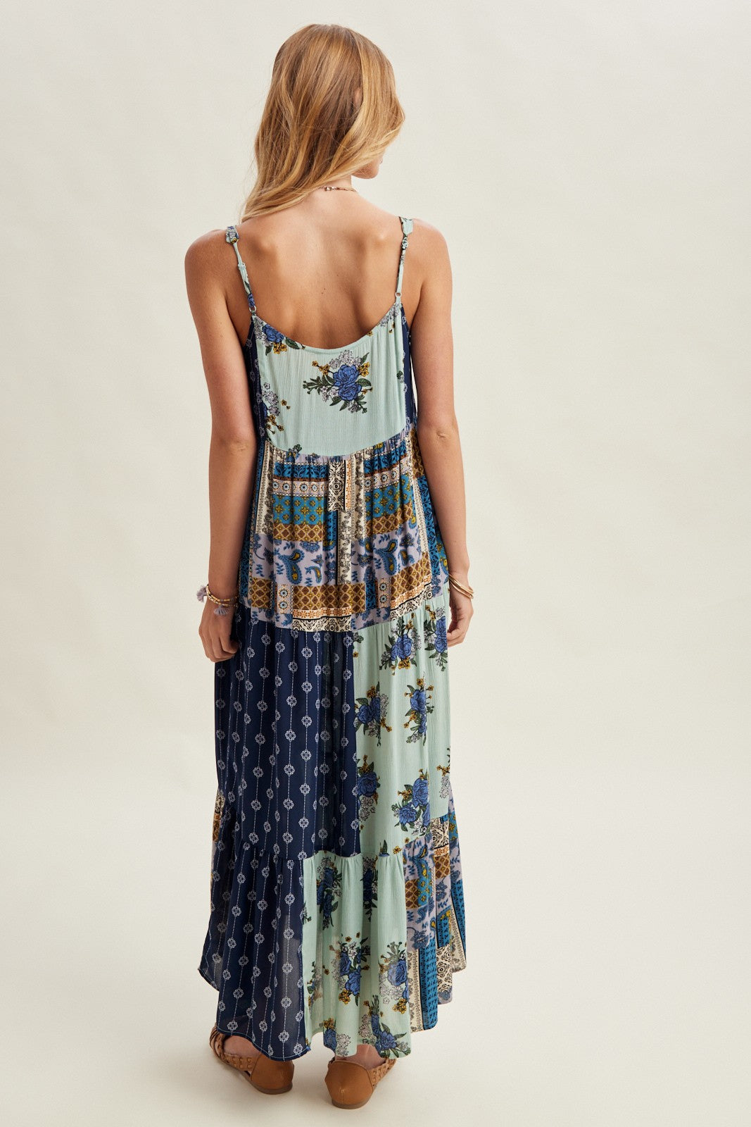 Woman wearing a long, patterned dress with a neutral background