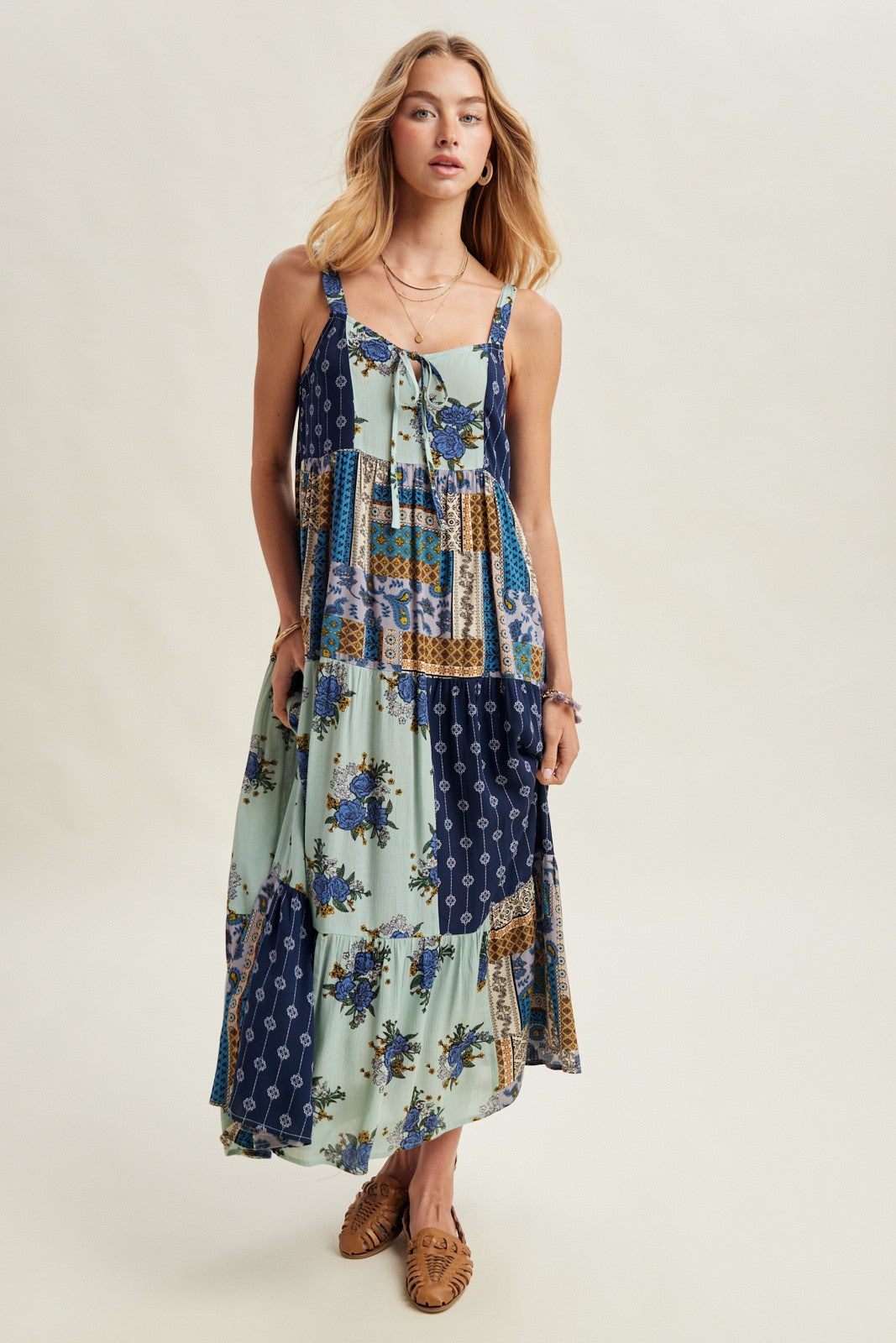 Woman wearing a patchwork dress with floral patterns on a plain background