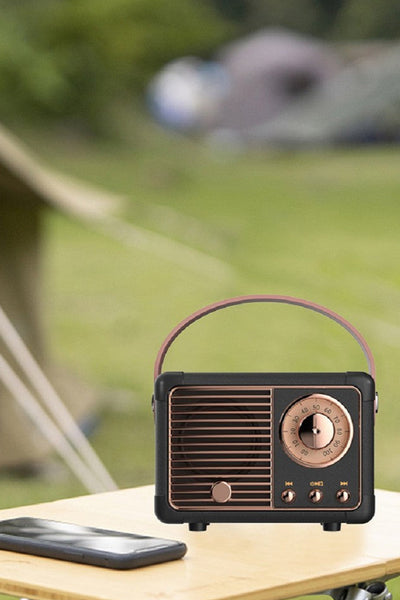 Vintage-style radio on a table with a blurred camping scene in the background