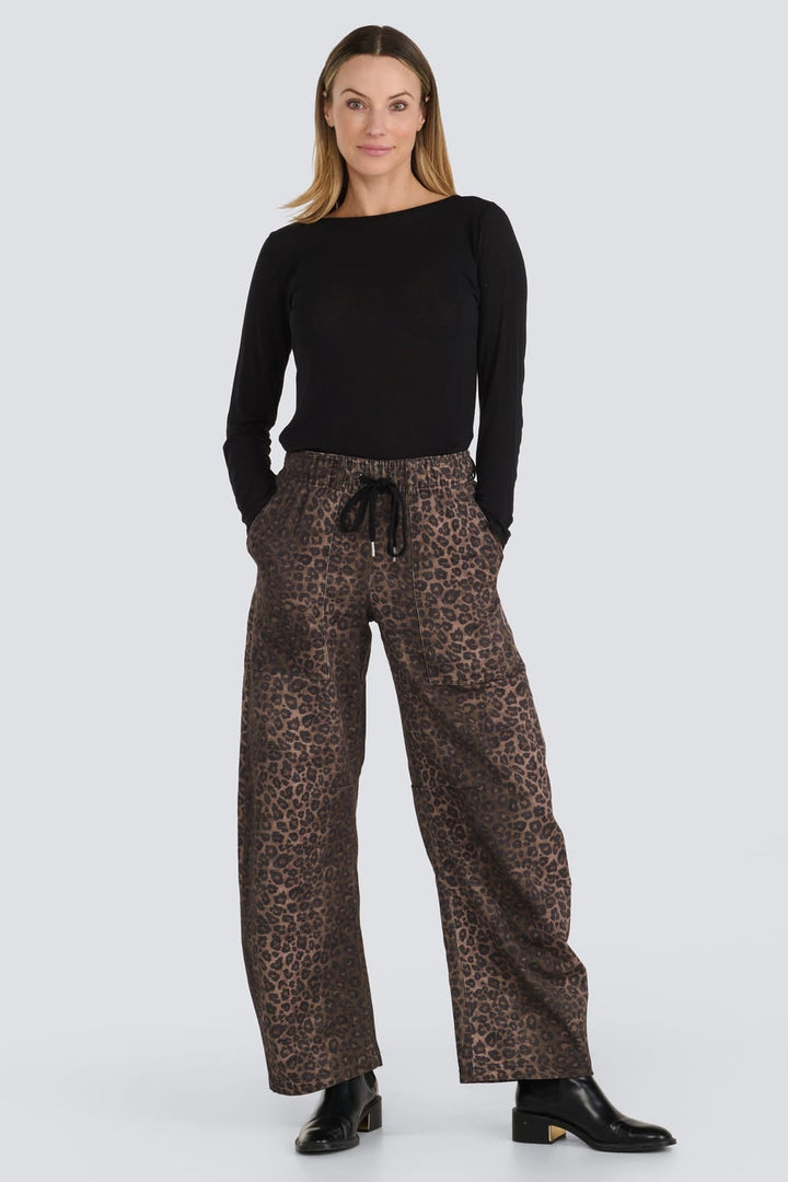 A woman modeling a black long-sleeve top and brown leopard-print wide-leg trousers with a drawstring waist, standing against a light gray studio background.