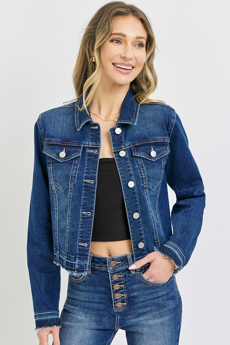 Woman wearing a blue denim jacket and jeans on a plain background