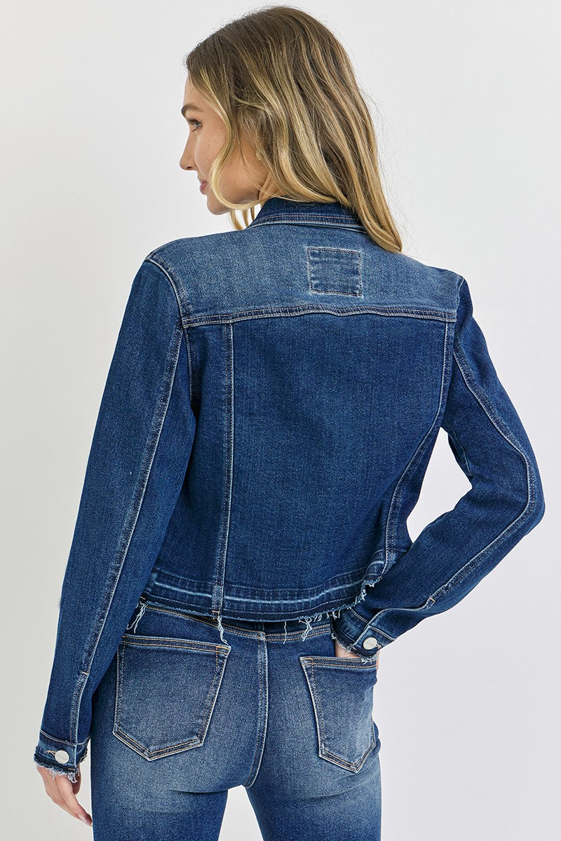 Woman wearing a blue denim jacket and jeans on a light gray background