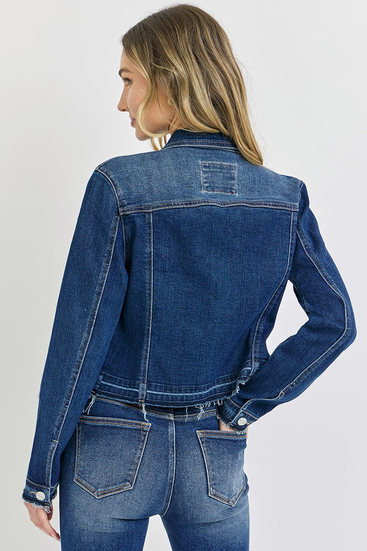 Woman wearing a blue denim jacket and jeans on a light gray background