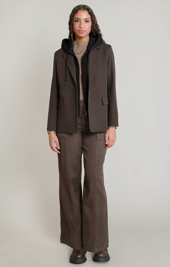 Woman wearing a brown jacket and pants on a plain background