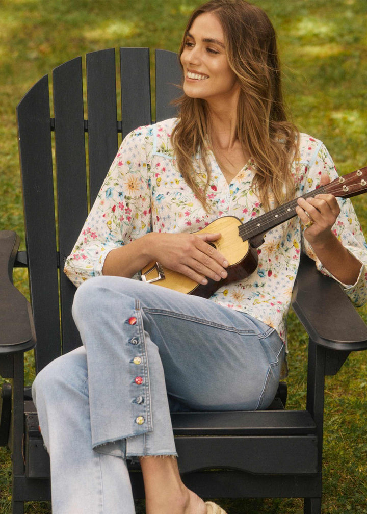 Woman playing a ukulele in a black Adirondack chair outdoors.