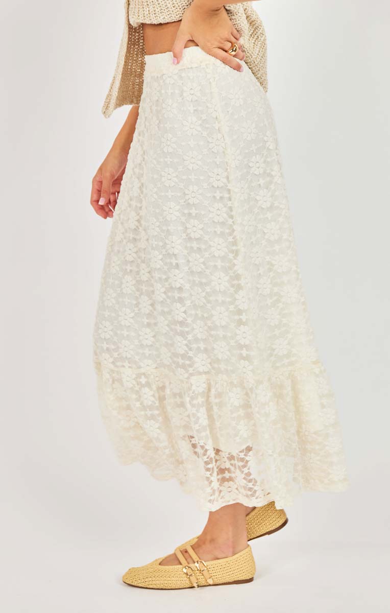 Person wearing a white lace skirt with yellow shoes on a light gray background