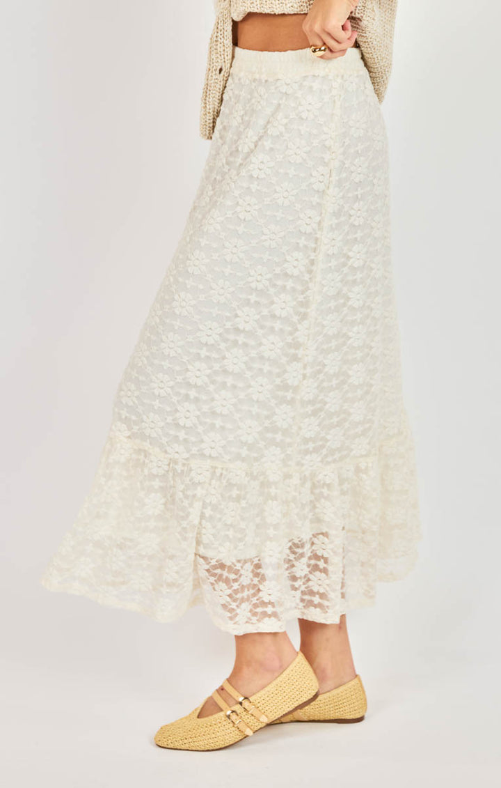 Person wearing a white lace skirt with yellow shoes on a plain background