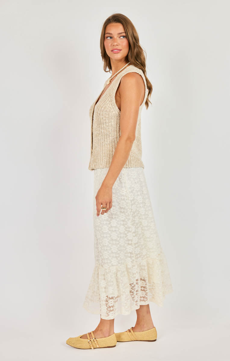 Woman wearing a sleeveless top and lace skirt on a white background