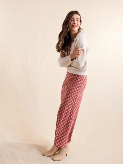 A woman modeling a long-sleeve cream knit cardigan and a red-and-white diamond-patterned maxi skirt, standing against a plain beige studio backdrop.