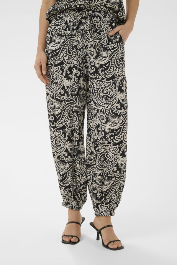 Person wearing black and white patterned pants on a white background