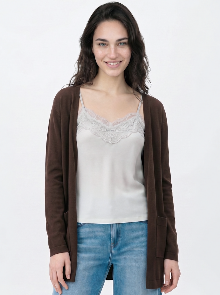 Woman wearing a brown cardigan over a white top and blue jeans on a white background