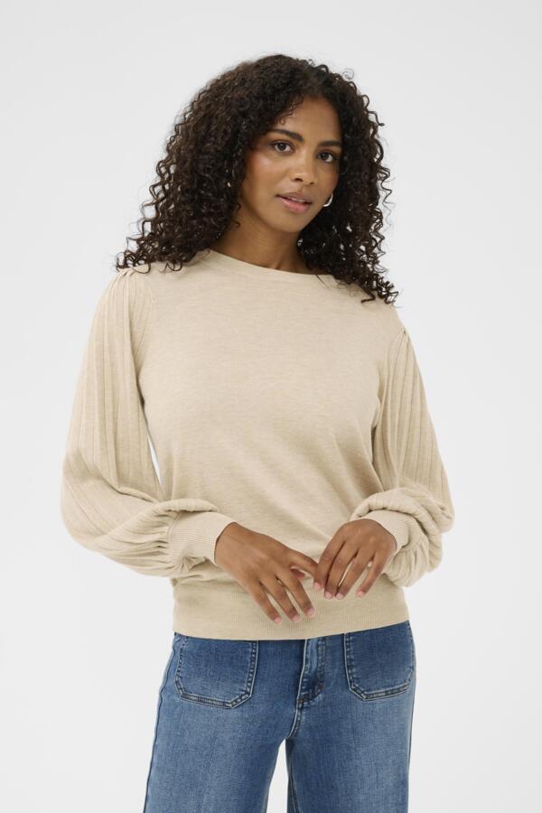 Woman wearing a beige sweater and blue jeans on a white background