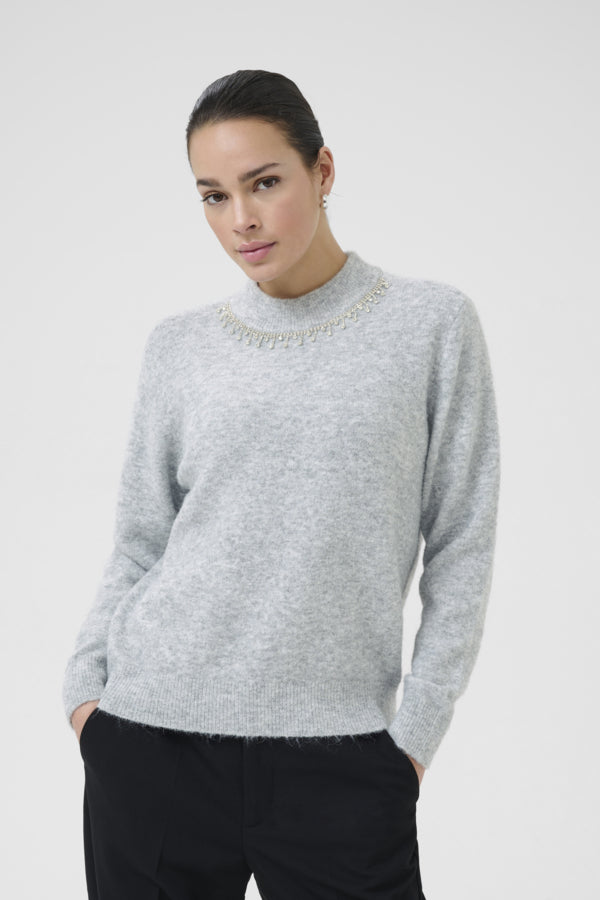 Woman wearing a gray sweater against a white background