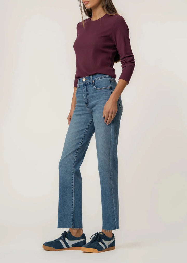 Person wearing a maroon sweater, blue jeans, and navy shoes on a white background