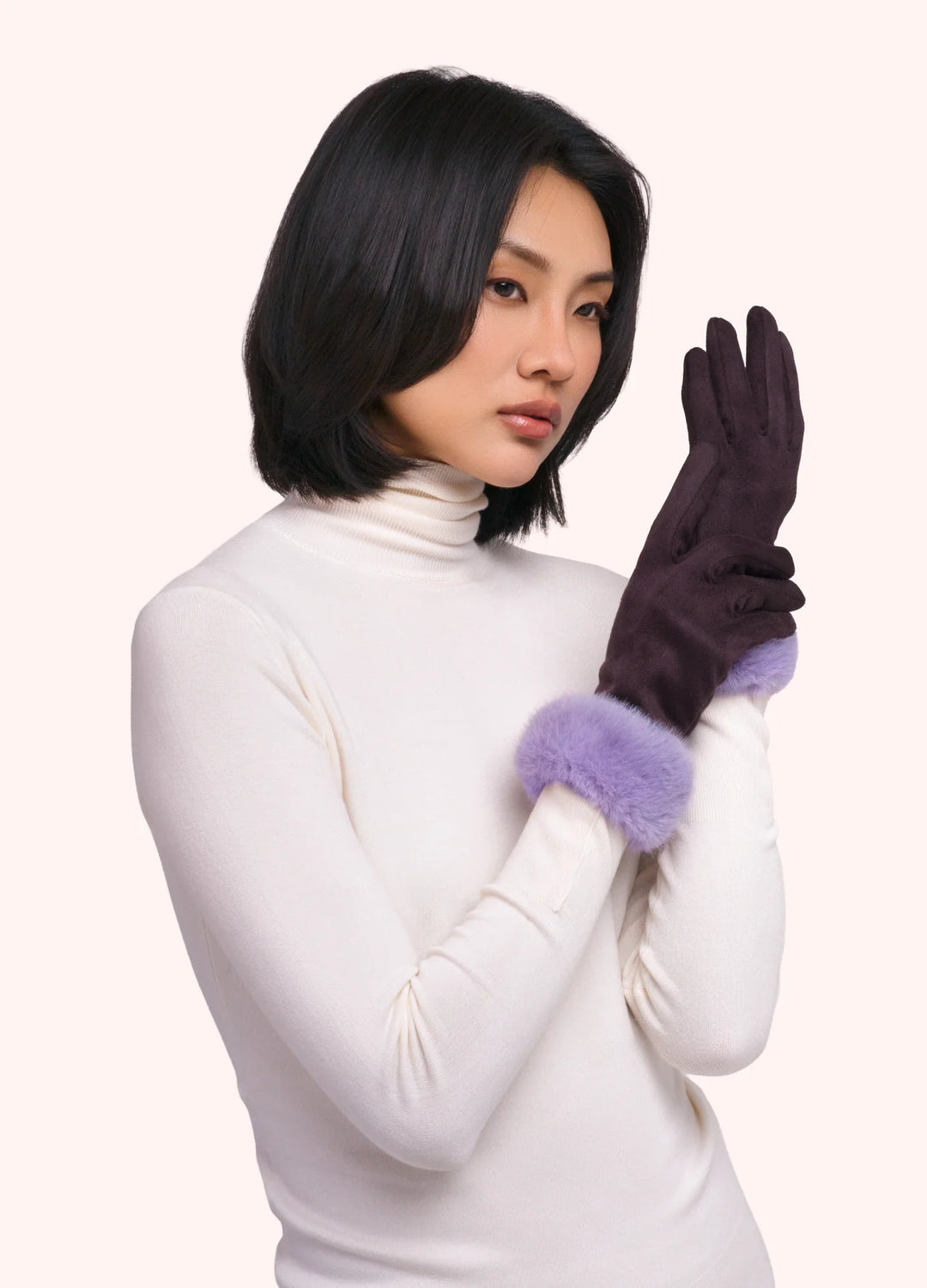 Woman wearing a white turtleneck and two-tone gloves on a white background
