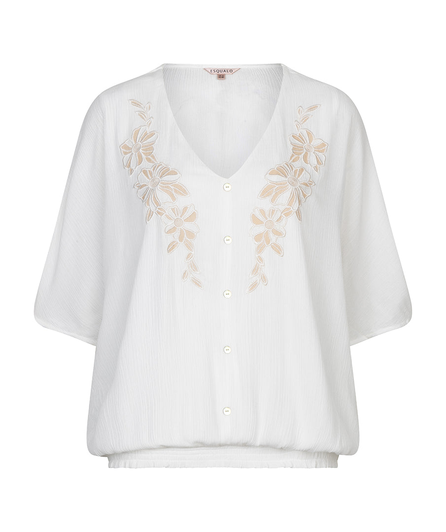 White blouse with floral embroidery on a white background