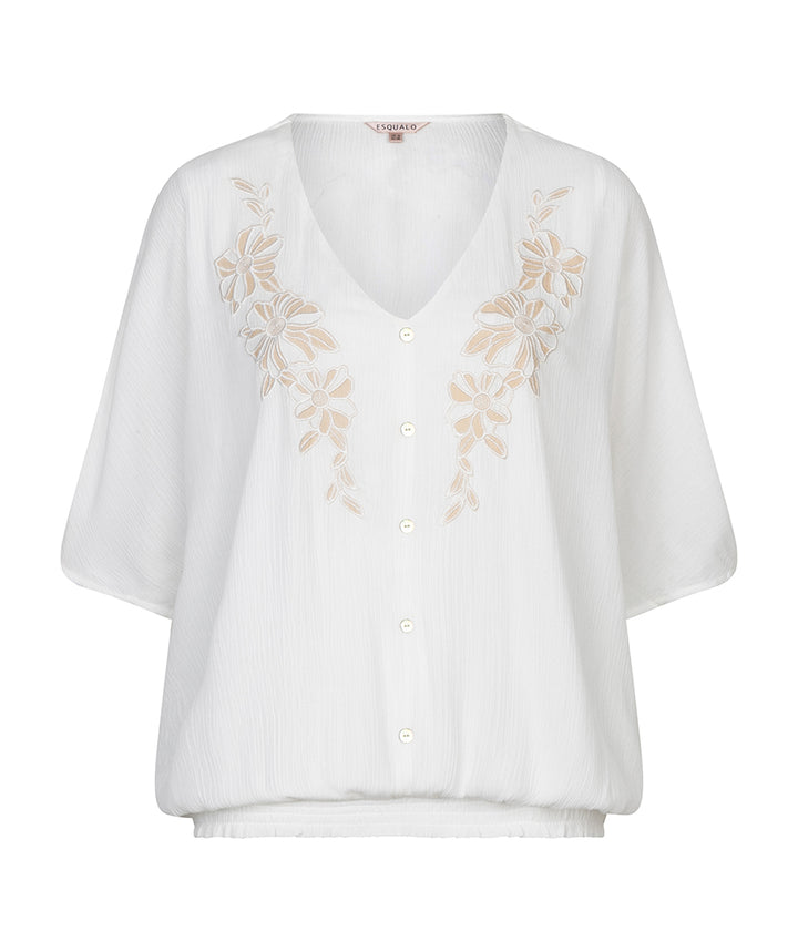 White blouse with floral embroidery on a white background