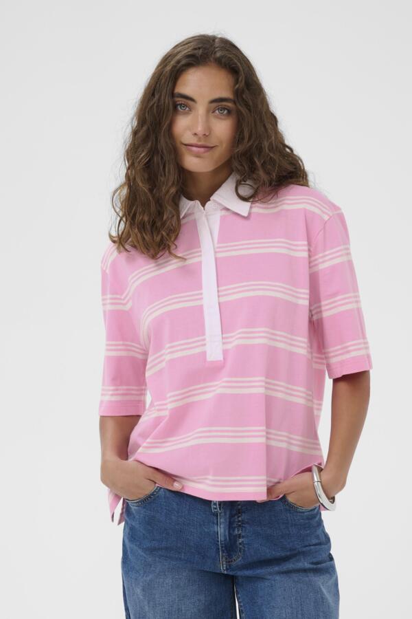 Woman wearing a pink and white striped polo shirt with blue jeans on a plain background