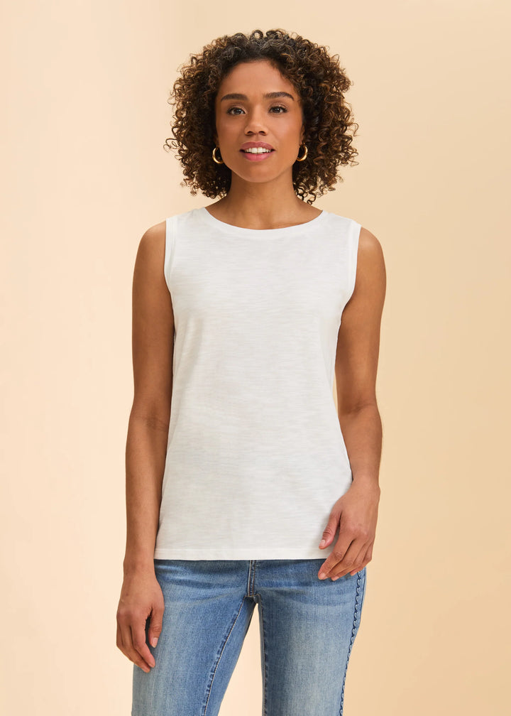 Woman wearing a white sleeveless top and blue jeans on a beige background