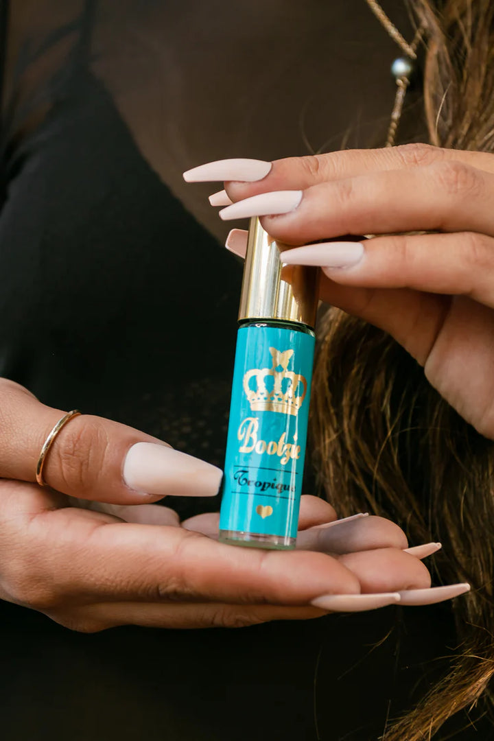 Person holding a blue and gold bottle of Bootzie Warm Vanilla+Coconut