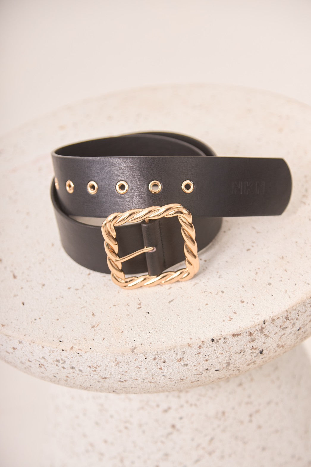 Black belt with a gold buckle on a textured surface