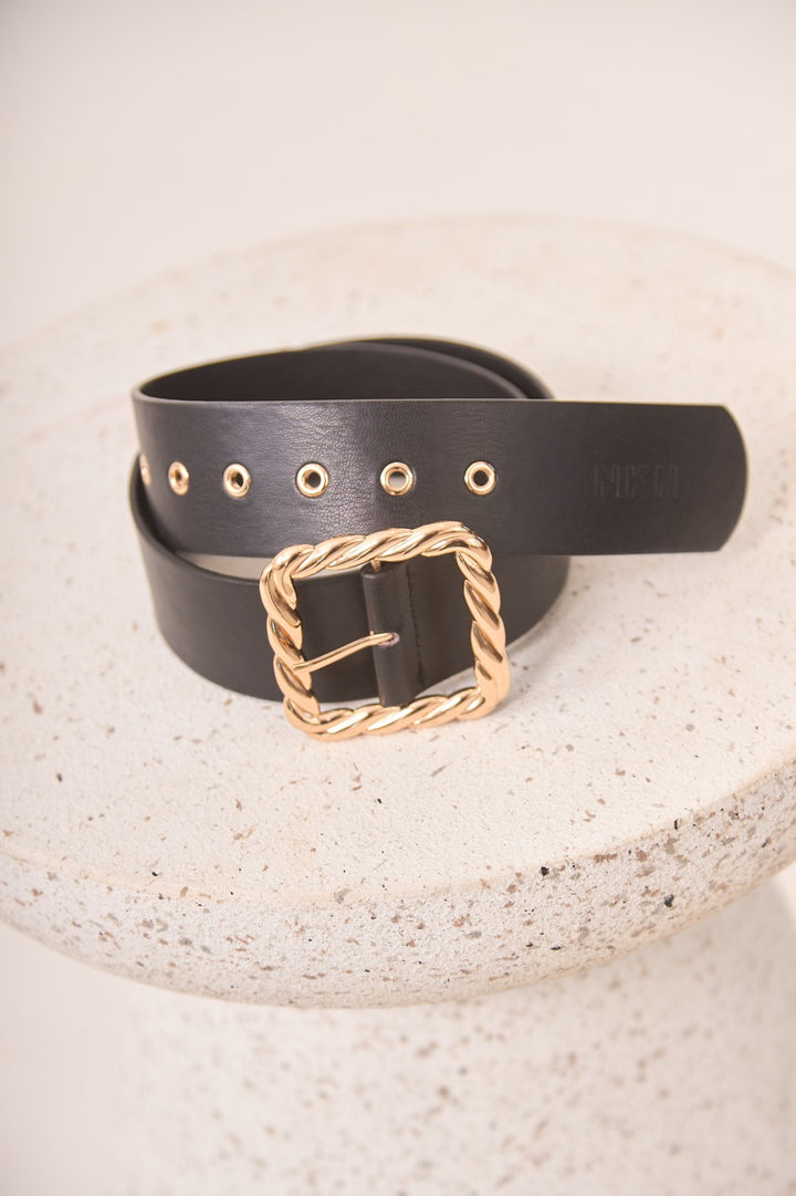 Black belt with a gold buckle on a textured surface