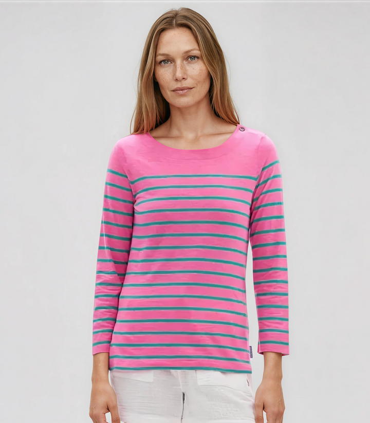Woman wearing a pink and blue striped sweater with white shorts on a plain background
