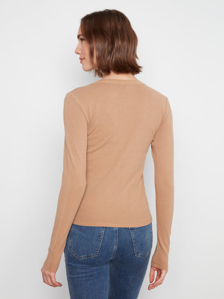 Woman wearing a beige long-sleeve top and blue jeans on a white background