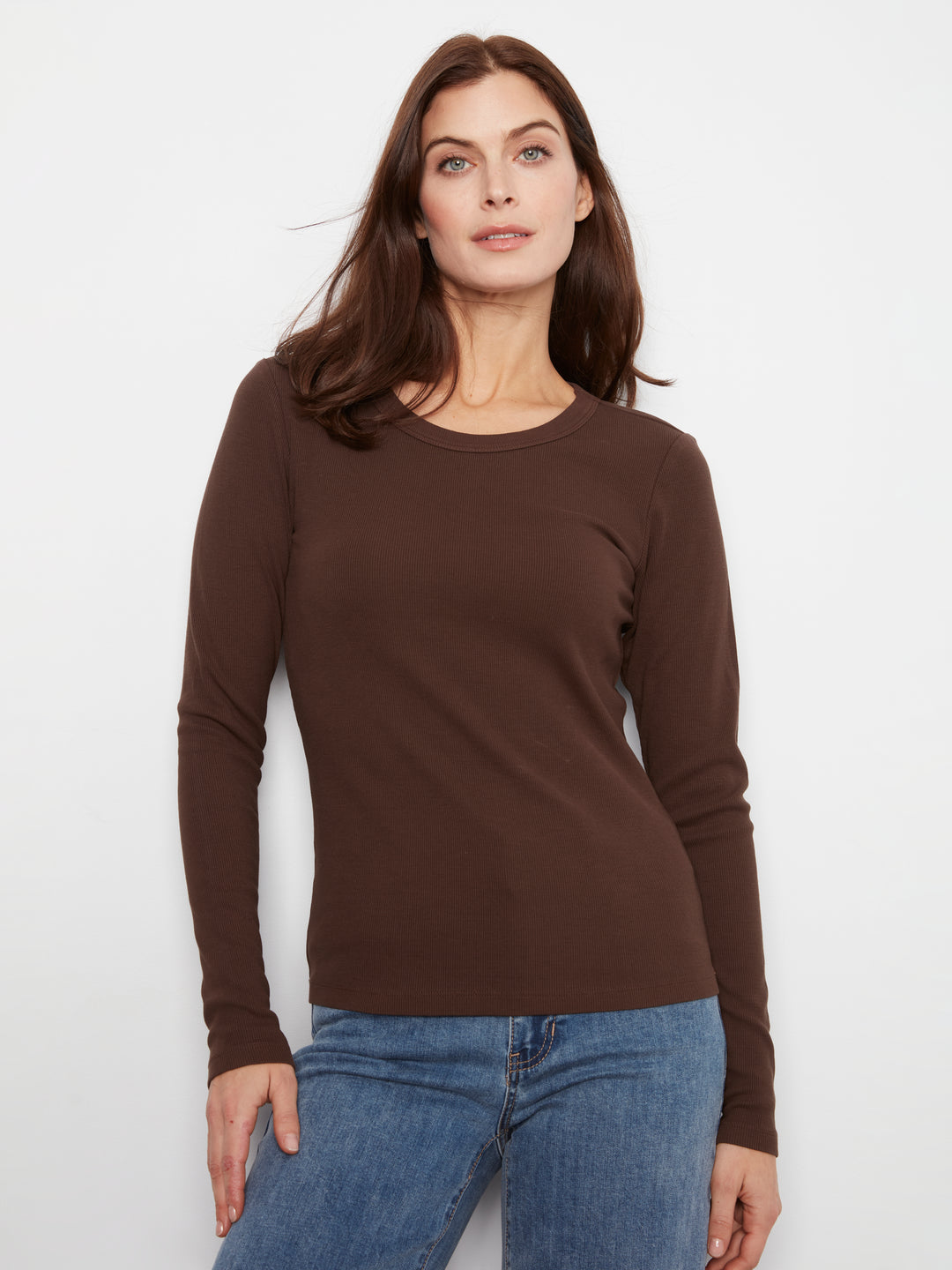 Woman wearing a brown long-sleeve top and blue jeans on a white background