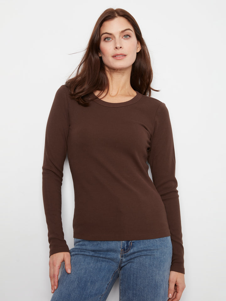 Woman wearing a brown long-sleeve top and blue jeans on a white background