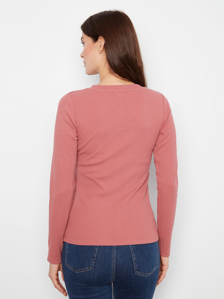 Woman wearing a pink long-sleeve top and blue jeans on a white background