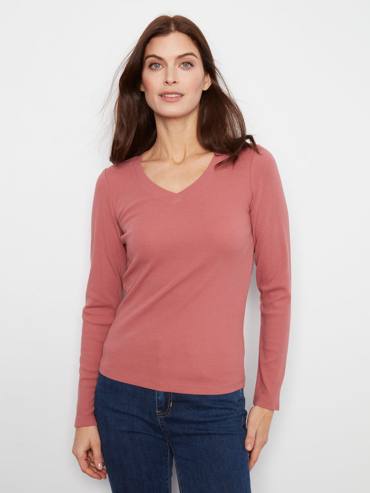 Woman wearing a pink long-sleeve top and blue jeans on a white background