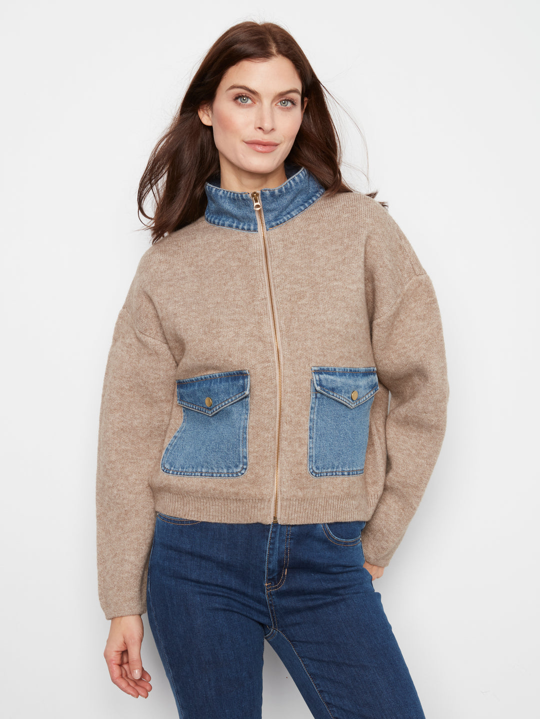 Woman wearing a beige jacket with denim accents on a white background