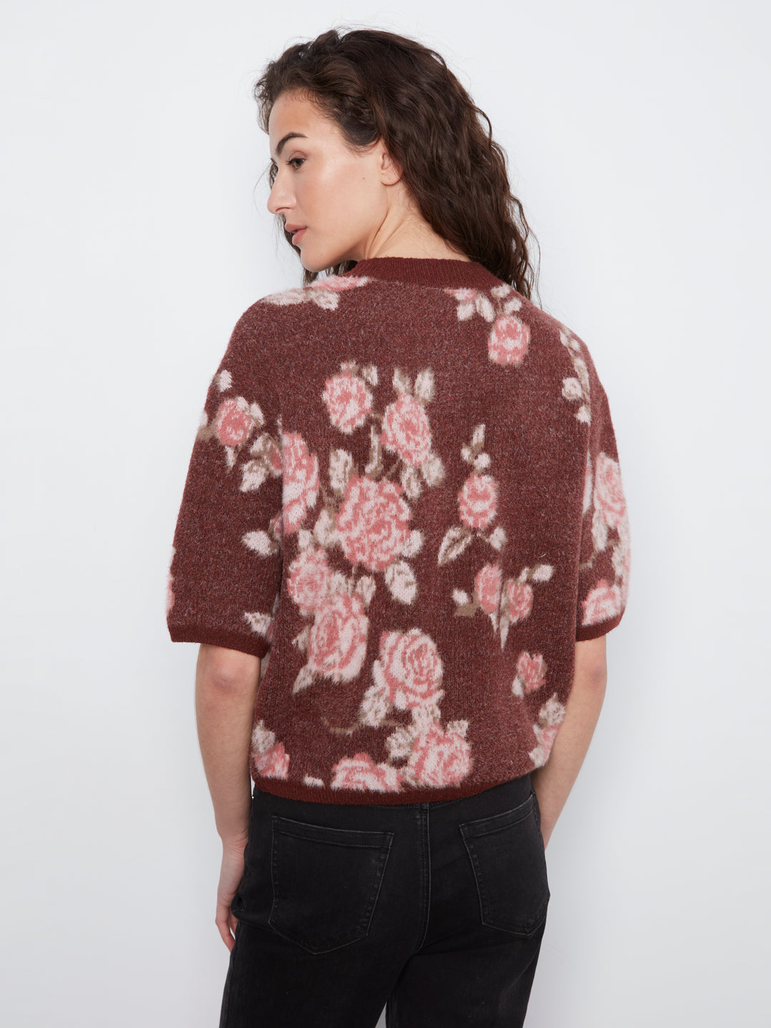 Woman wearing a brown floral-patterned sweater against a white background