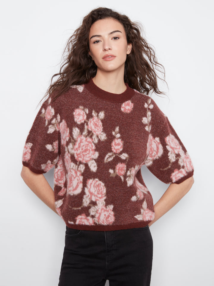 Woman wearing a maroon sweater with pink floral pattern on a white background