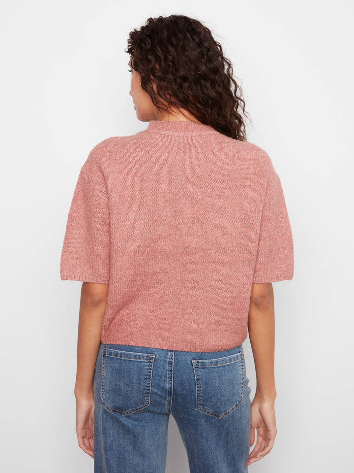 A woman viewed from the back wearing a dusty rose short-sleeve knit top and blue jeans against a plain white background.