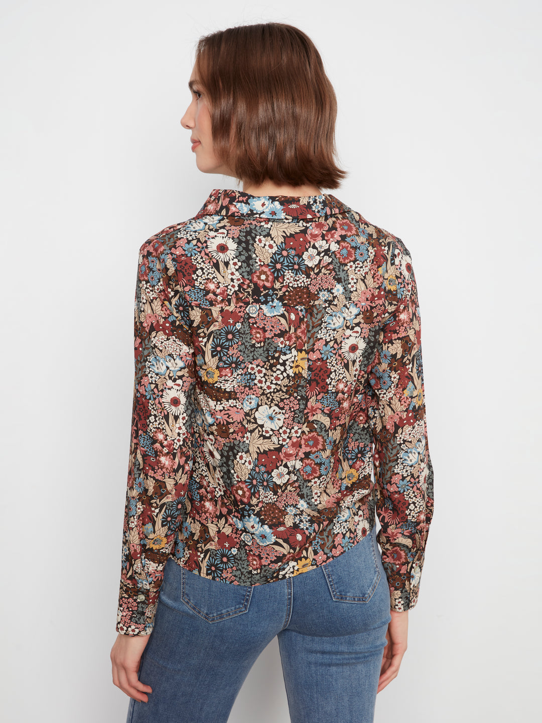 Woman wearing a floral blouse and blue jeans on a white background