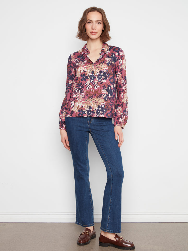 Woman wearing a floral blouse and blue jeans against a white background