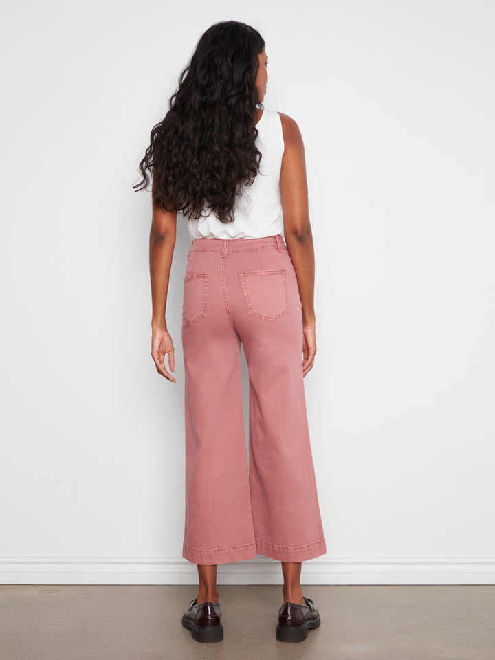 Person wearing pink pants and a white top against a white background