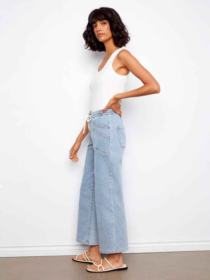 Woman wearing a white top and light blue jeans against a white background